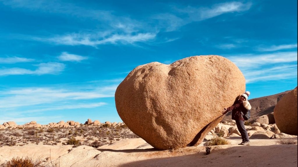 female solo travel hug a heart rock in Joshua Tree National park
